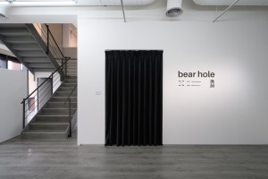 Entrance to bear hole exhibition. Black curtain covering a doorway in a white wall. 