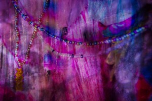 image of pearls hanging infront of purple and blue cloth as a background